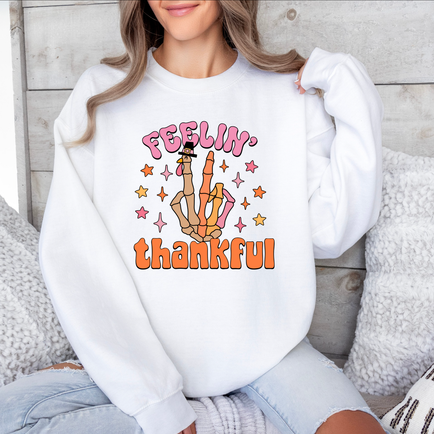 a woman sitting on a bed wearing a white sweatshirt