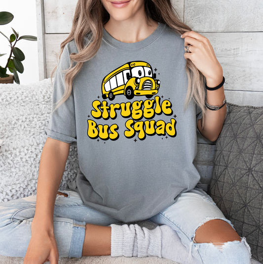 a woman sitting on a couch wearing a grey tshirt that says struggle bus