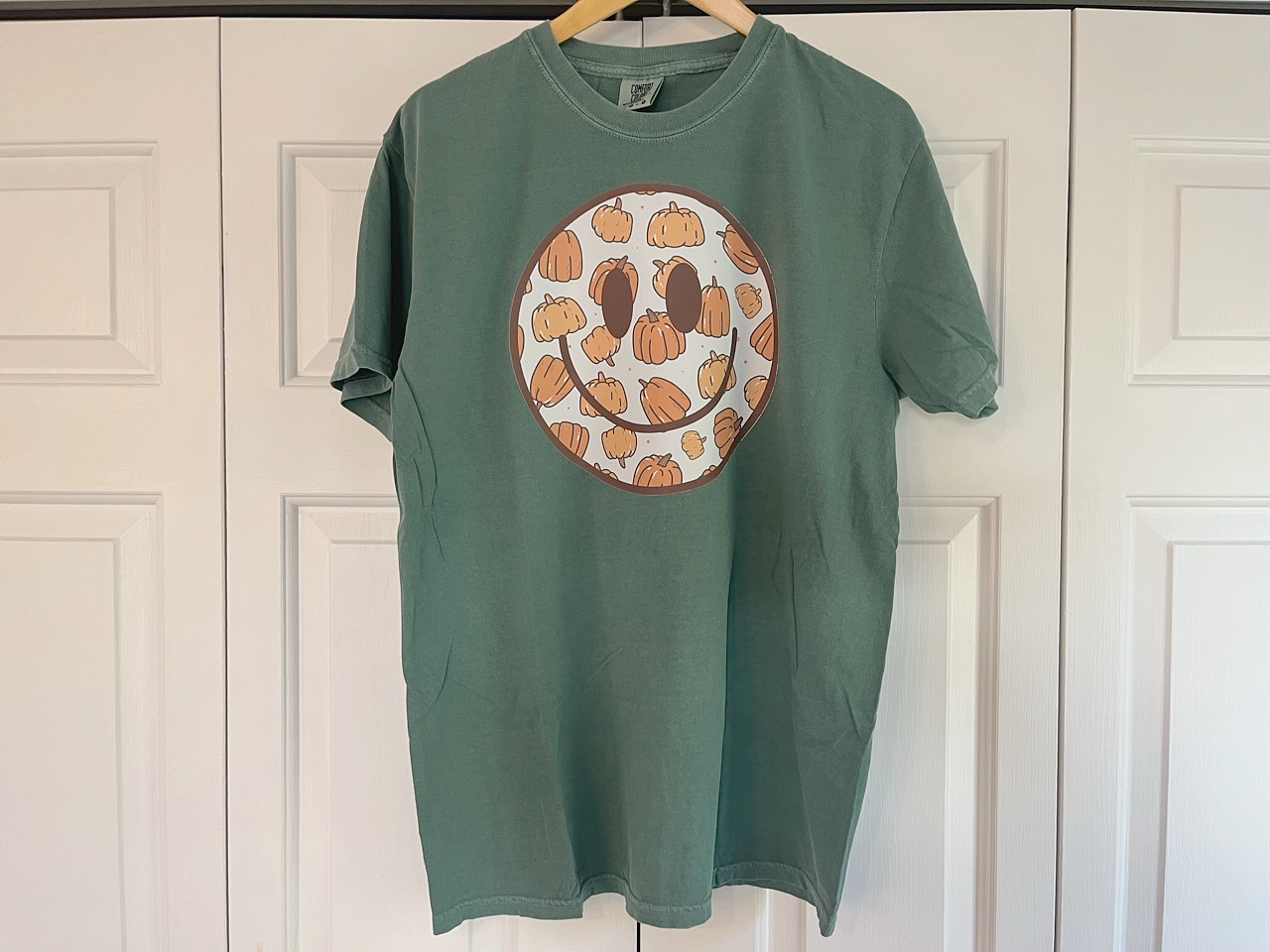 a green t - shirt with a smiley face drawn on it