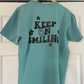 a t - shirt that says keep on smiling hanging on a door