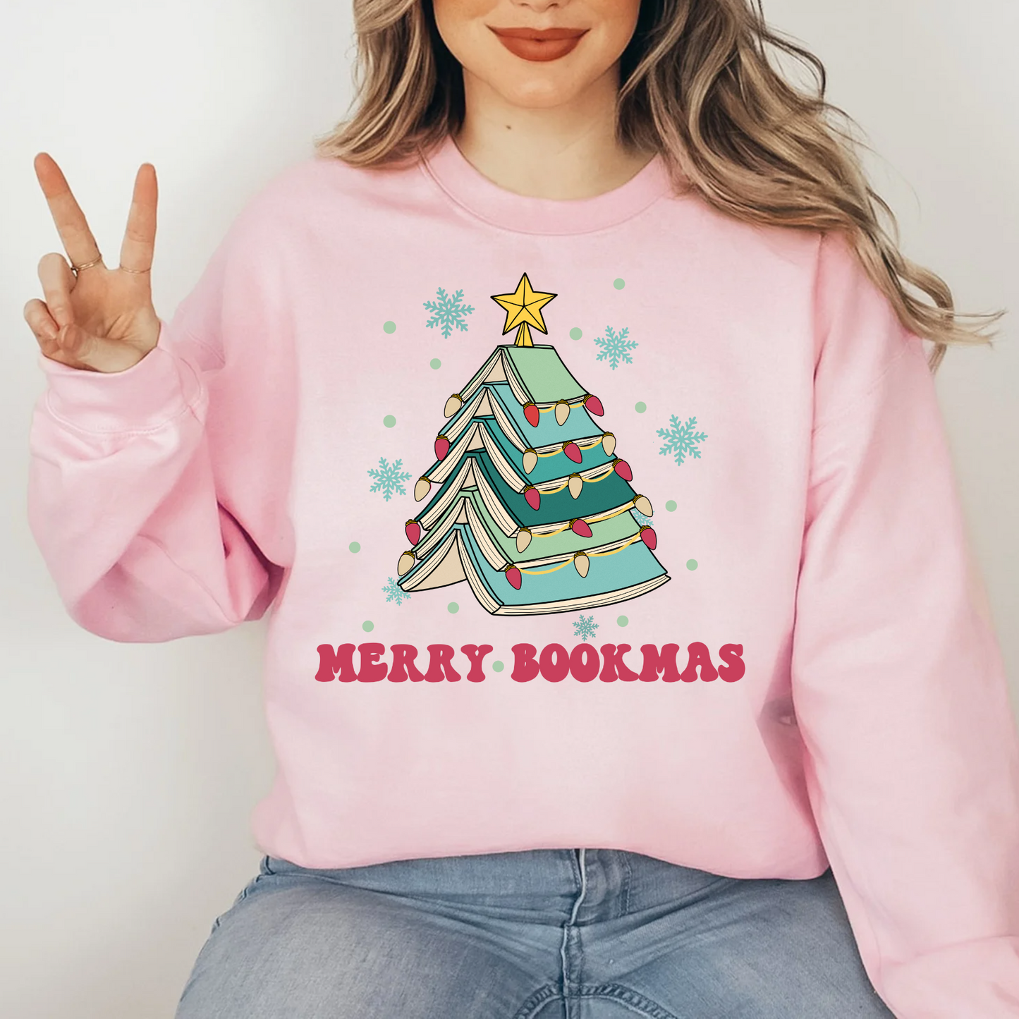 a woman wearing a pink sweatshirt with a christmas tree on it