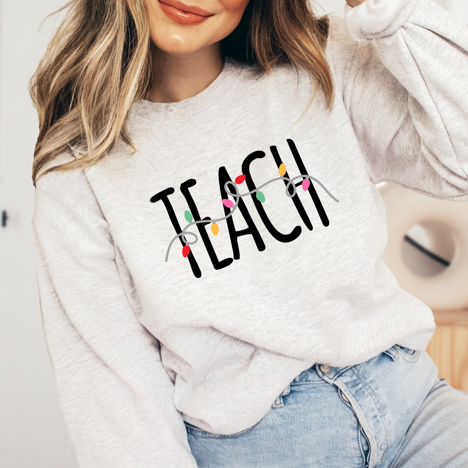 a woman wearing a sweatshirt that says teach