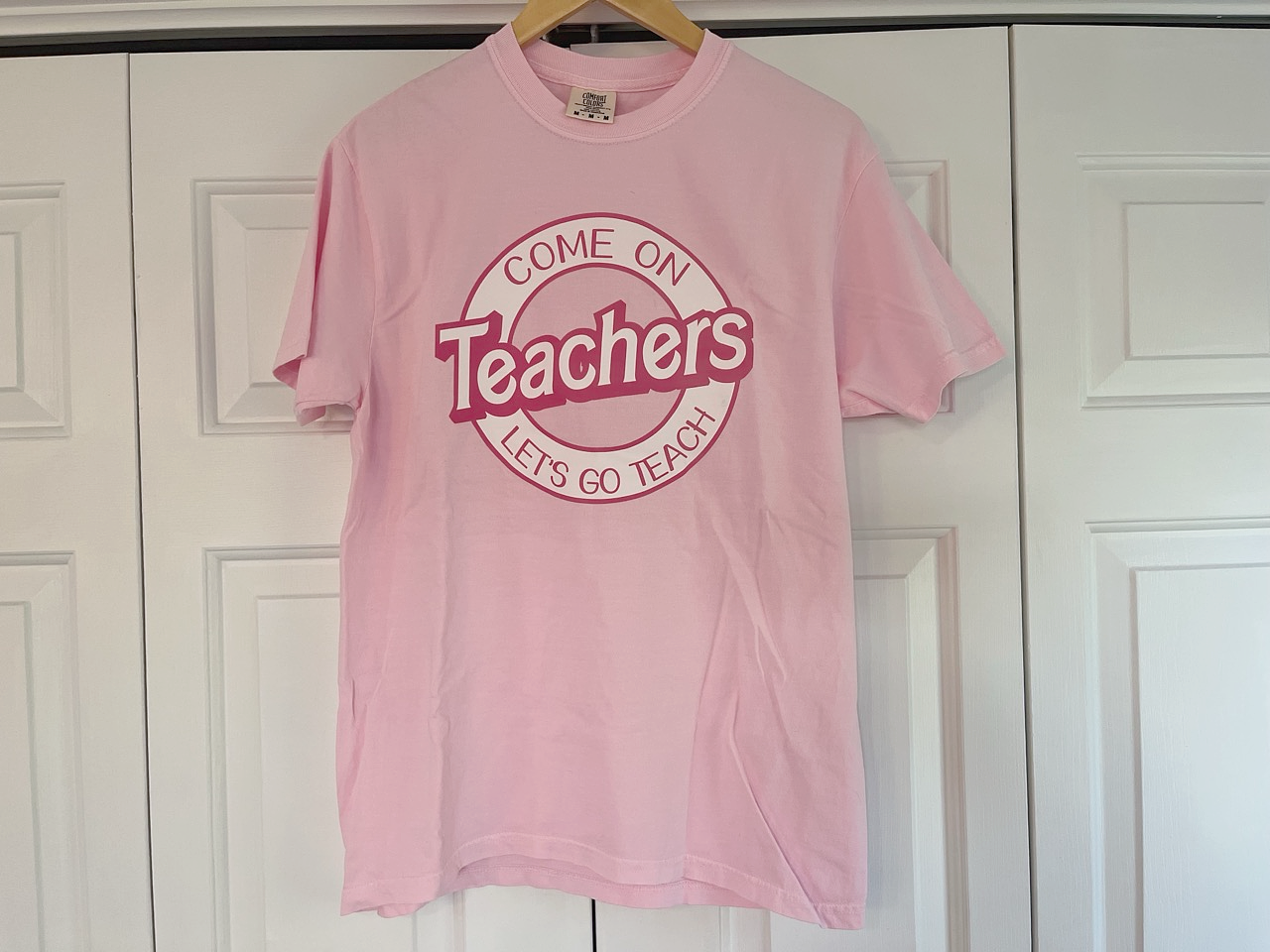 a pink t - shirt hanging on a white door