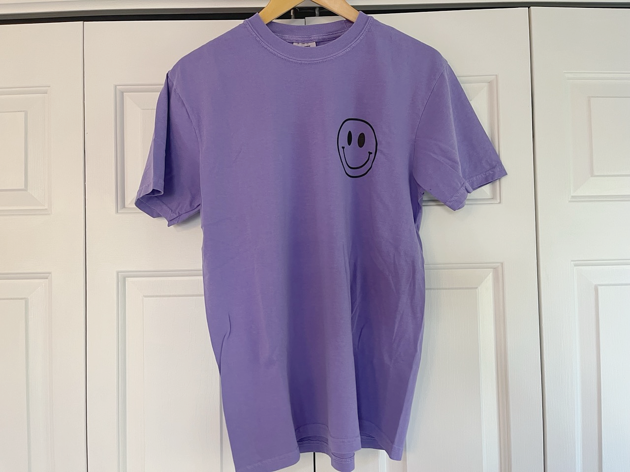 a purple shirt with a smiley face drawn on it