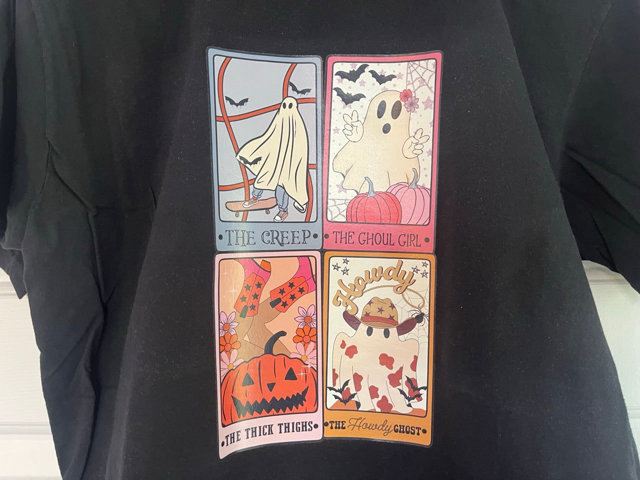 a black t - shirt with a picture of a ghost and pumpkins on it