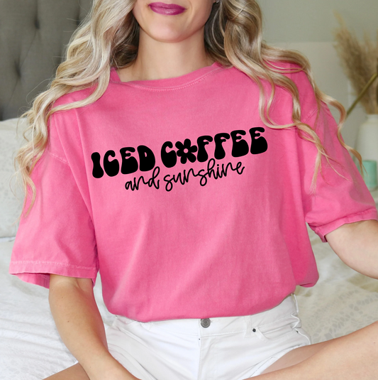 a woman sitting on a bed wearing a pink shirt that says iced coffee and sunshine