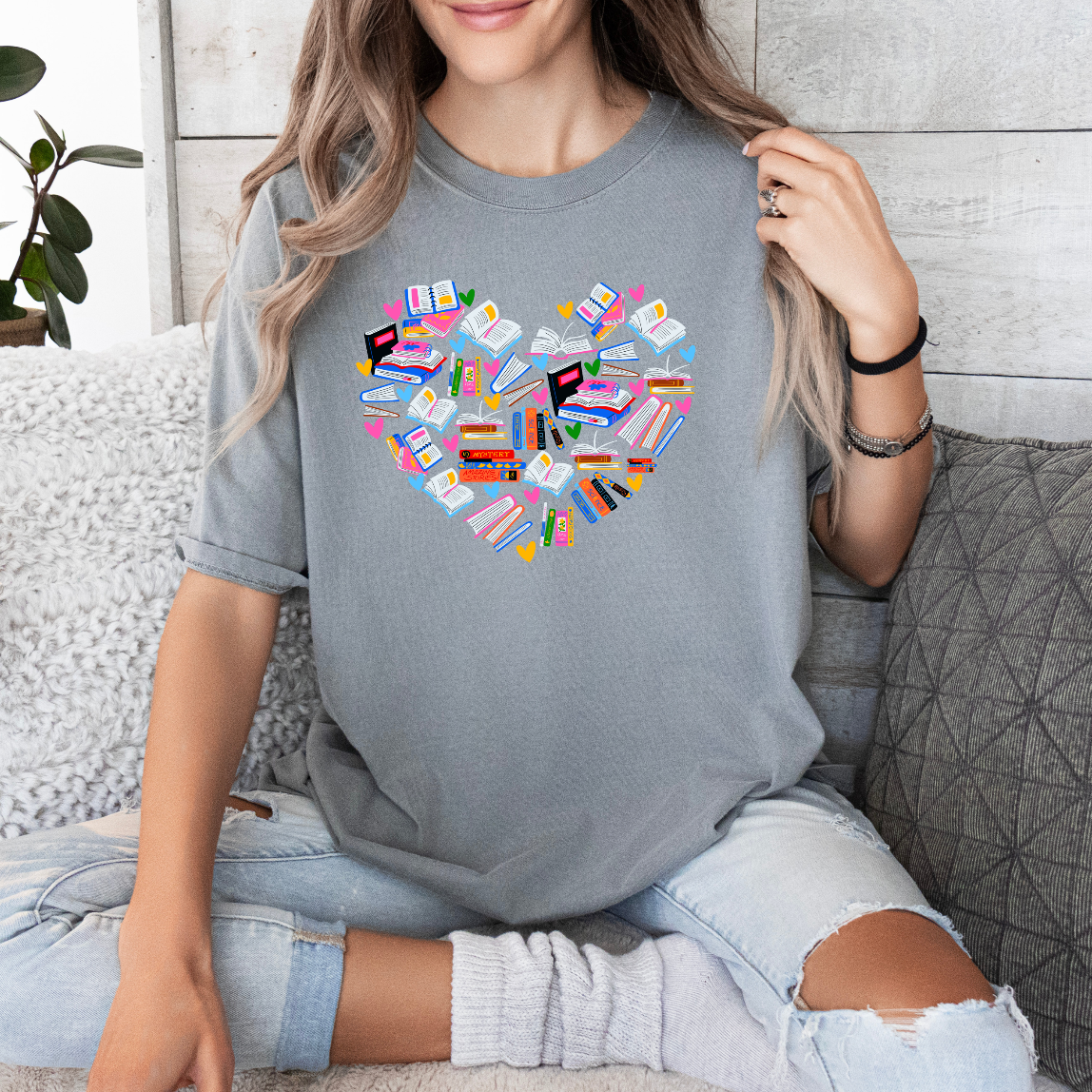 a woman sitting on a couch holding up a heart shaped t - shirt