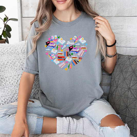 a woman sitting on a couch holding up a heart shaped t - shirt