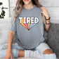 a woman sitting on a couch wearing a t - shirt that says tired