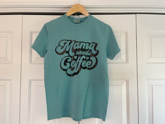 a t - shirt that says mama needs coffee hanging on a door