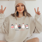 a woman sitting on a bed wearing a sweatshirt with cats on it