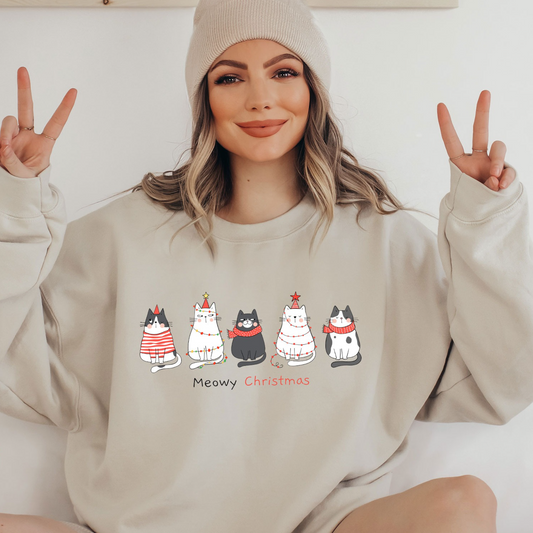 a woman sitting on a bed wearing a sweatshirt with cats on it